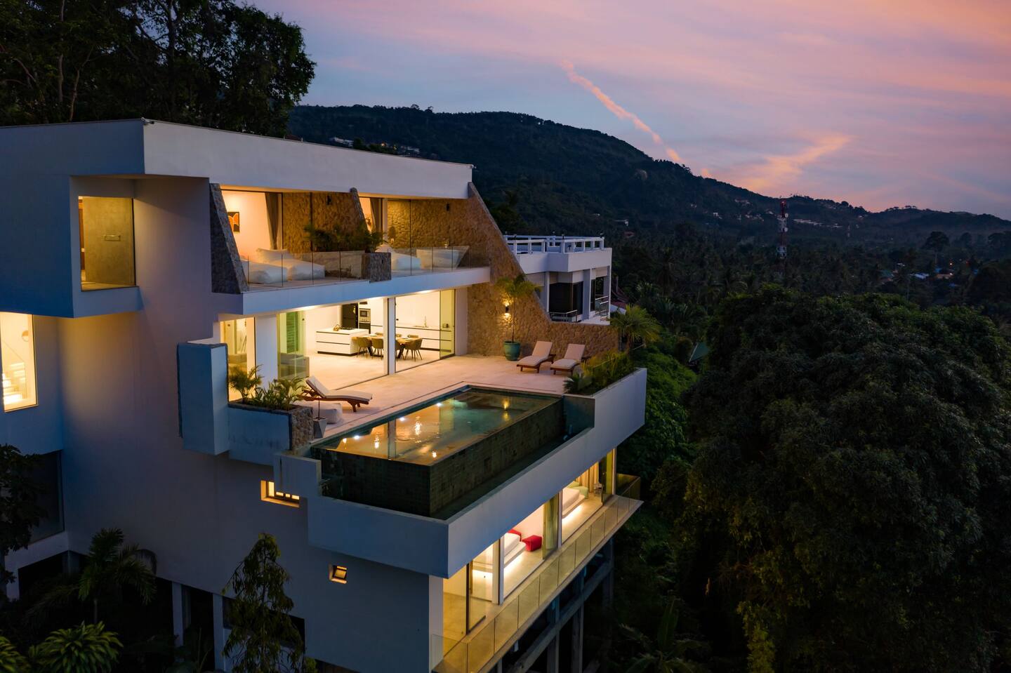 Multi-level mansion exterior at sunset with pool and terraces